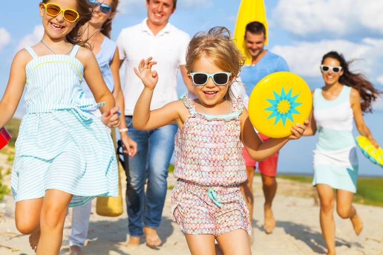 family walking to beach carrying beach toys and gear