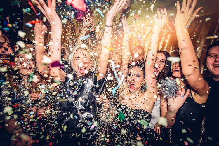 People ringing in the new year with falling confetti all around them