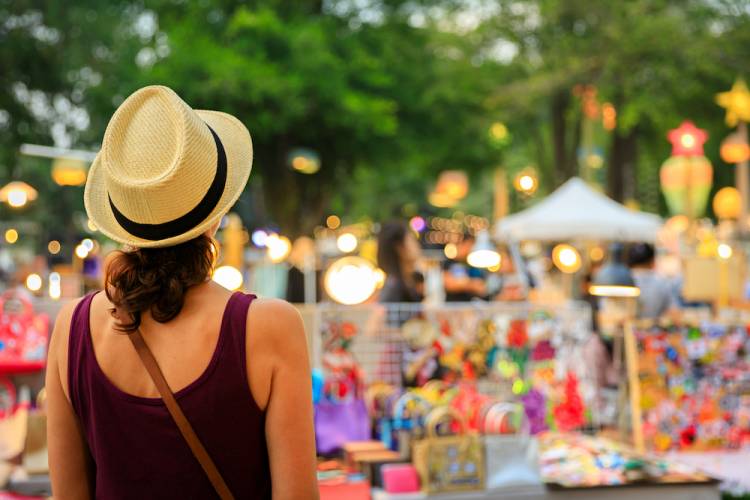 woman with back turned looking toward an outdoor craft market