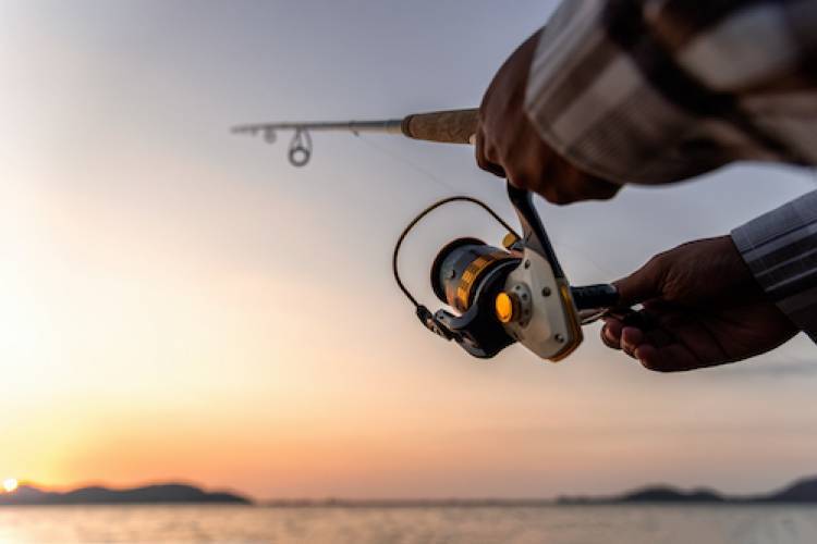 casting a fishing line with the sun setting in the background