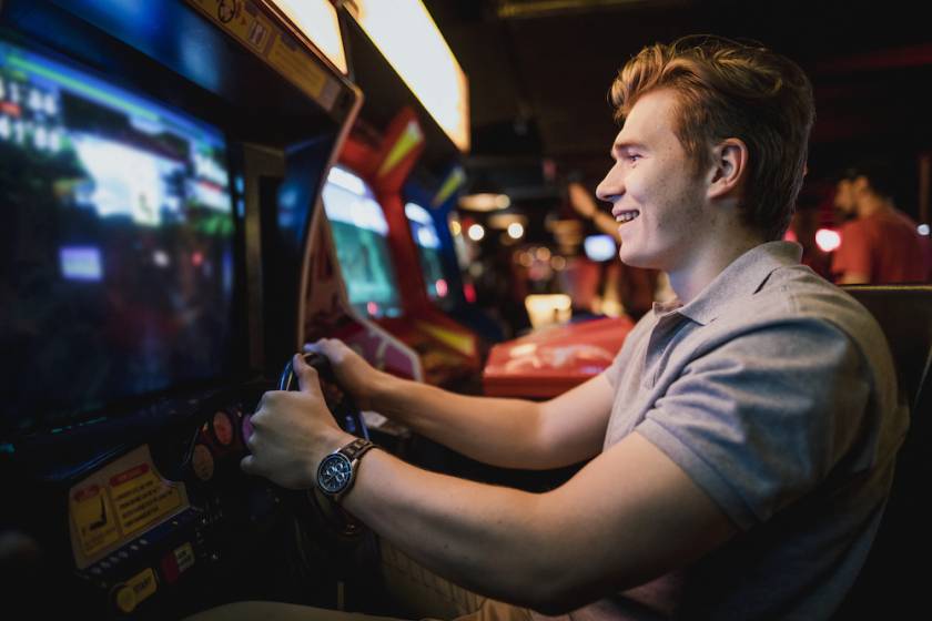 guy at an arcade playing a driving game