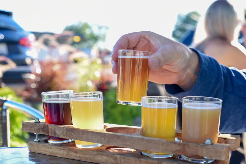 man lifting a sample glass from a beer flight