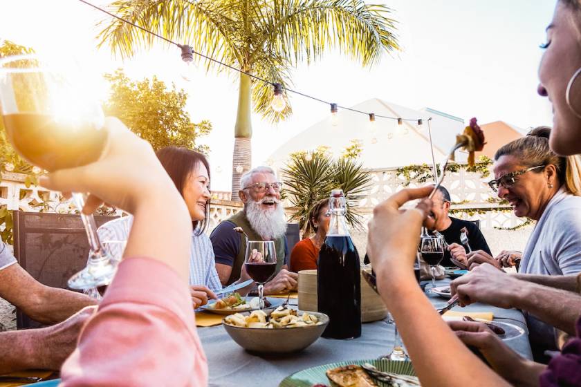 group at a restaurant's outdoor table with palm trees overhead