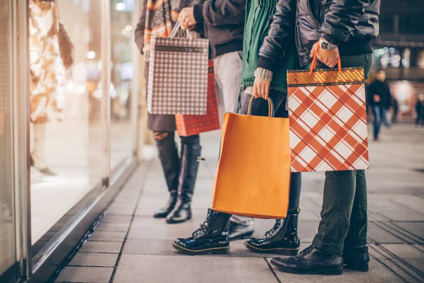 people holiday shopping holding bags outside a shop window