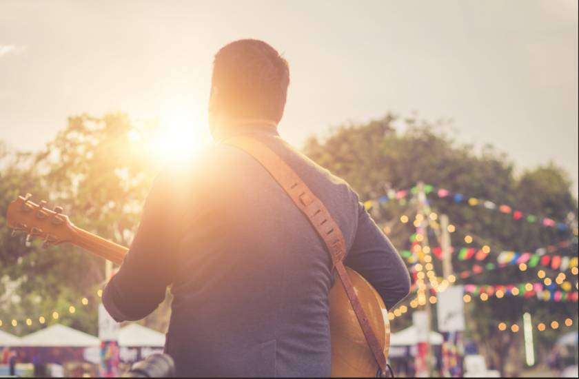 man playing music on stage at an outdoor festival 