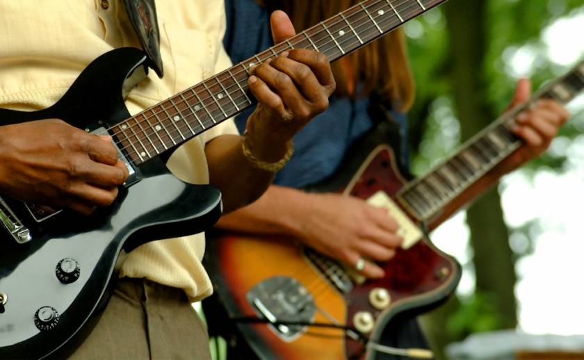 two guitar players on stage at an outdoor summer concert