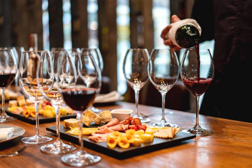 person pouring sample glasses of wine with a charcuterie board on a table